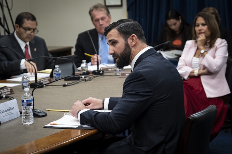 Acting FEMA administrator Cameron Hamilton speaks while seated at a table with several other people.
