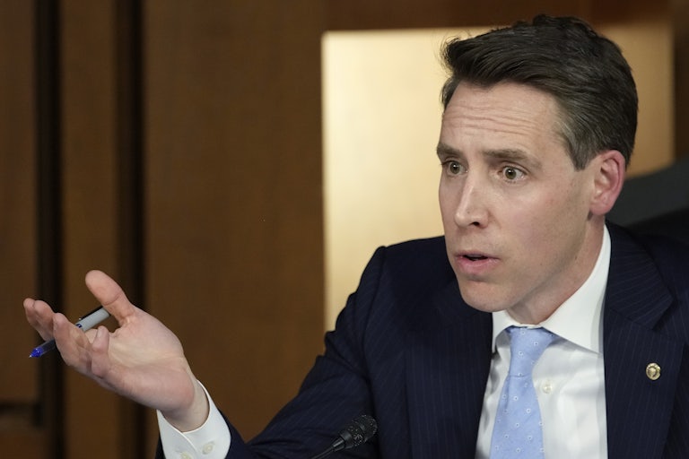 Josh Hawley looks exasperated and raises his hand in the air as if to question, "What?"