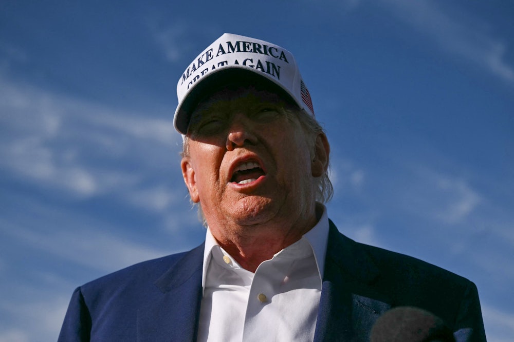Donald Trump yells outside while wearing a white MAGA cap.