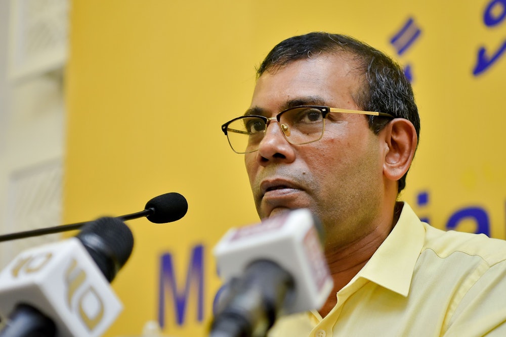 Mohamad Nasheed speaks in front of several microphones.