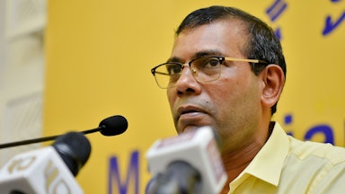 Mohamad Nasheed speaks in front of several microphones.