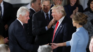 Bill Clinton shakes hands with Donald Trump as Melania looks on.