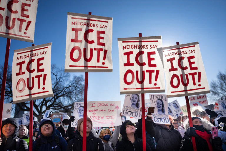 Students hold signs reading "Neighbors Say ICE OUT!" outside the Minnesota State Capitol.