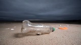 A plastic bottle lies on a beach.