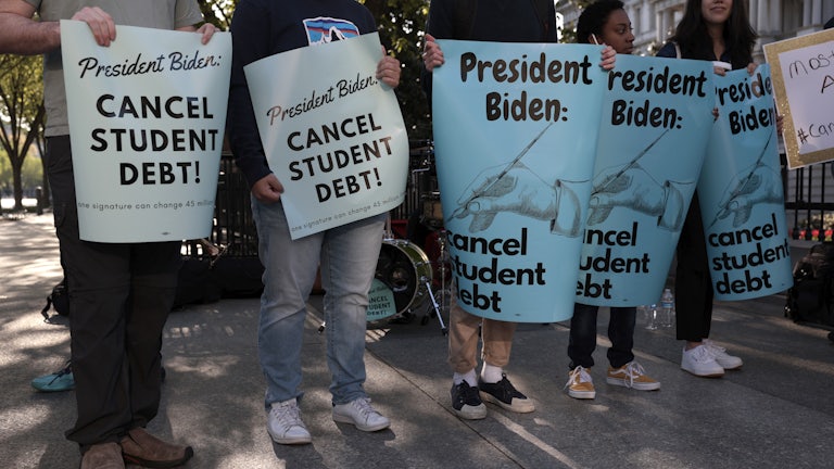Activists hold signs as they attend a Student Loan Forgiveness rally near the White House.