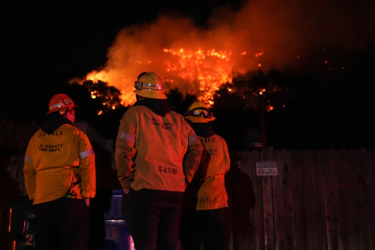 Firefighters in L.A. stand vigiliant as a large fire burns in the background