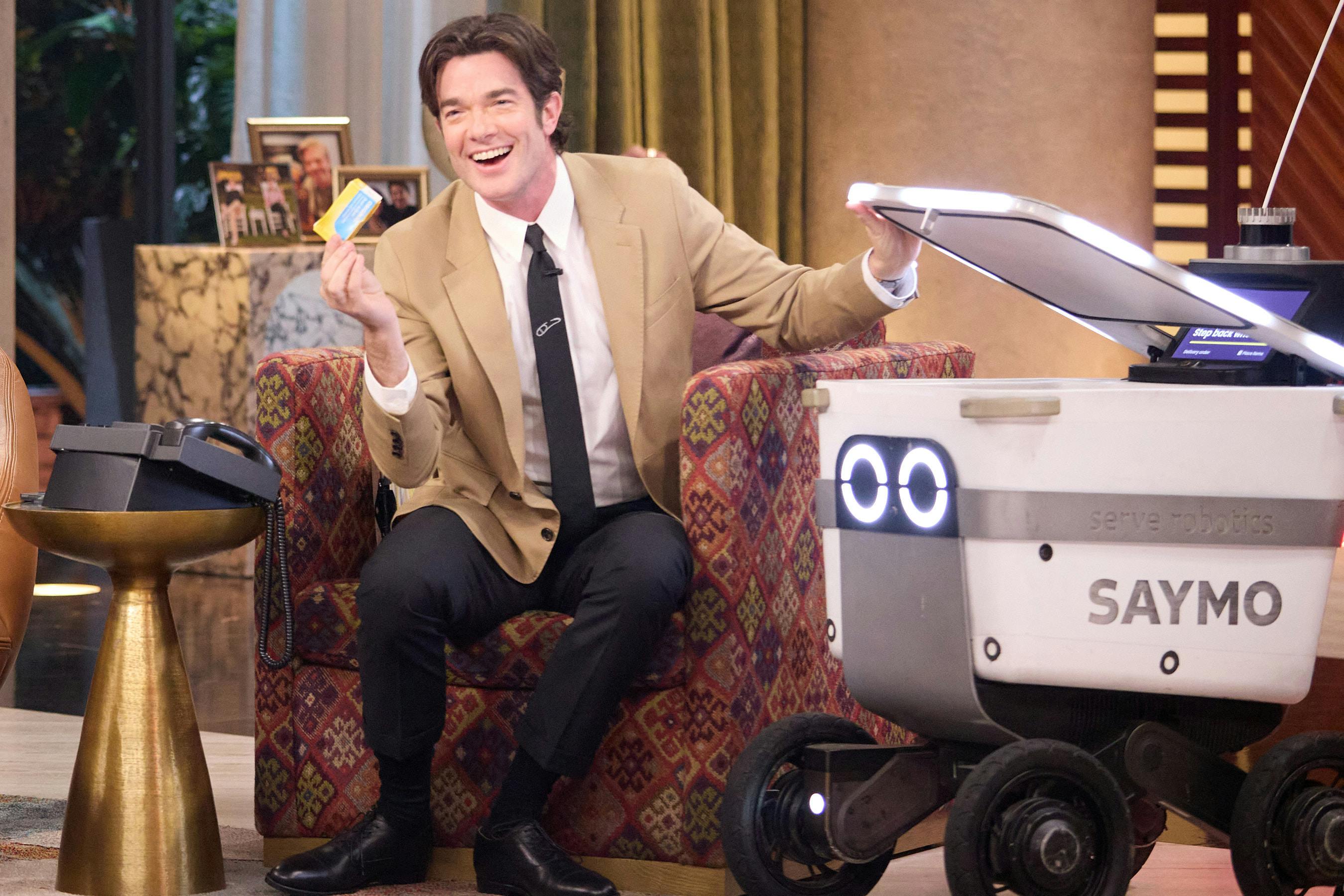 John Mulaney sits next to the “Saymo” delivery robot, which ranges freely around the set of “Everybody’s Live”