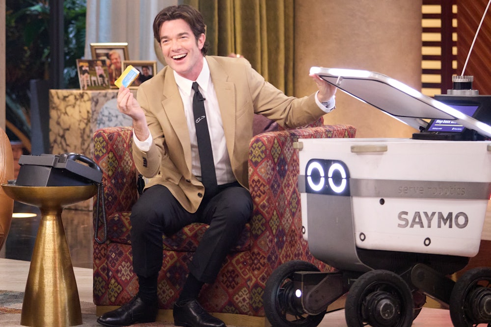 John Mulaney sits next to the “Saymo” delivery robot, which ranges freely around the set of “Everybody’s Live”