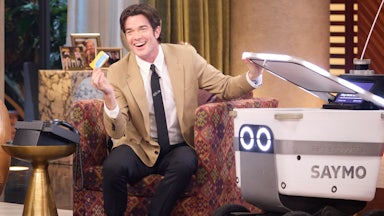 John Mulaney sits next to the “Saymo” delivery robot, which ranges freely around the set of “Everybody’s Live”