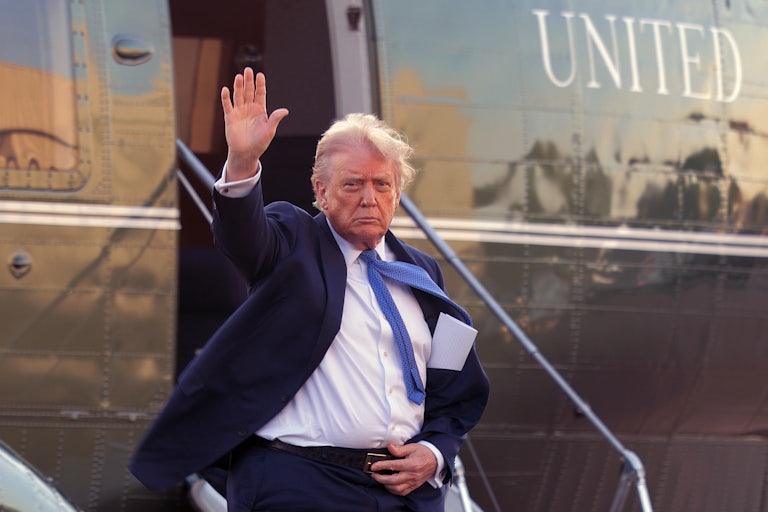 Donald Trump waves while getting off of a helicopter