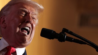 Donald Trump opens his mouth very wide as he speaks into a microphone