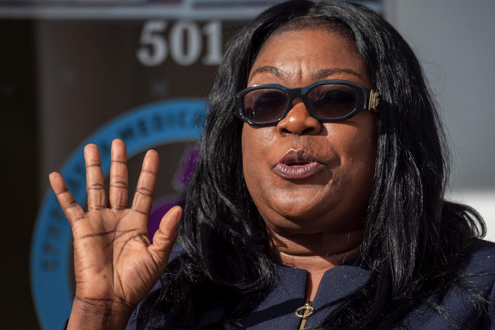 A woman holds up a hand while speaking.