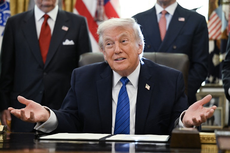 Donald Trump makes a shrugging motion while sitting at his desk in the Oval Office