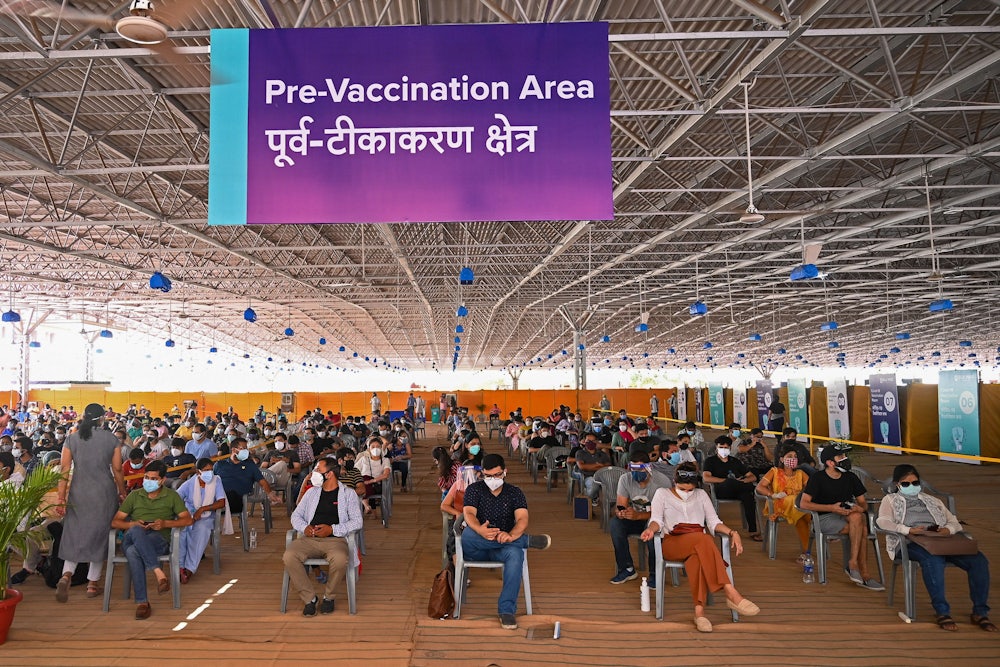 Lines of masked people sit in chairs.