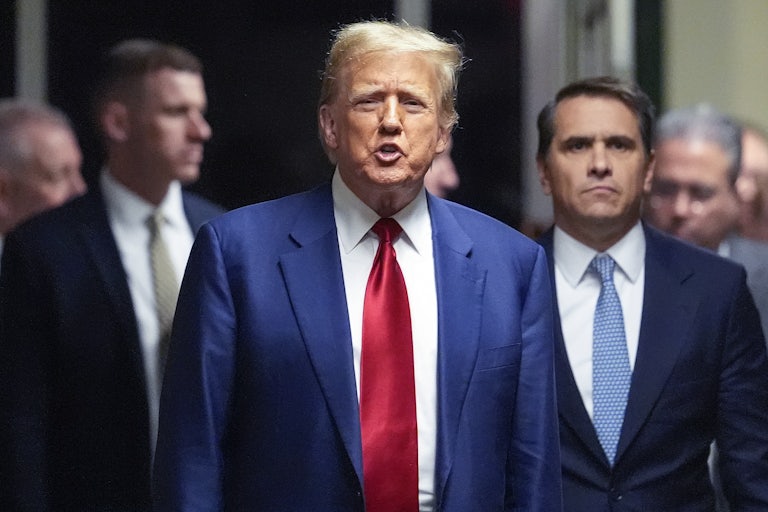 Donald Trump yells while others stand behind him