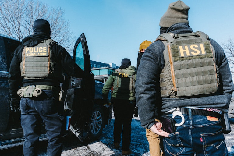 Federal immigration agents stand in a parking lot in Minneapolis.