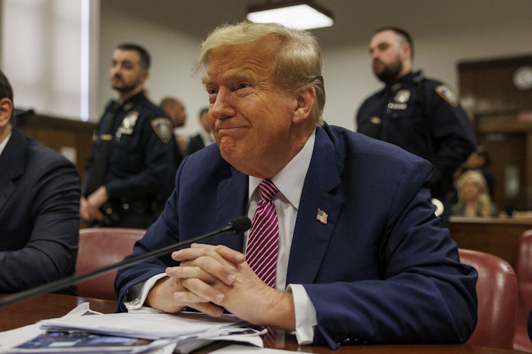 Donald Trump grimaces as he sits with his hands folded