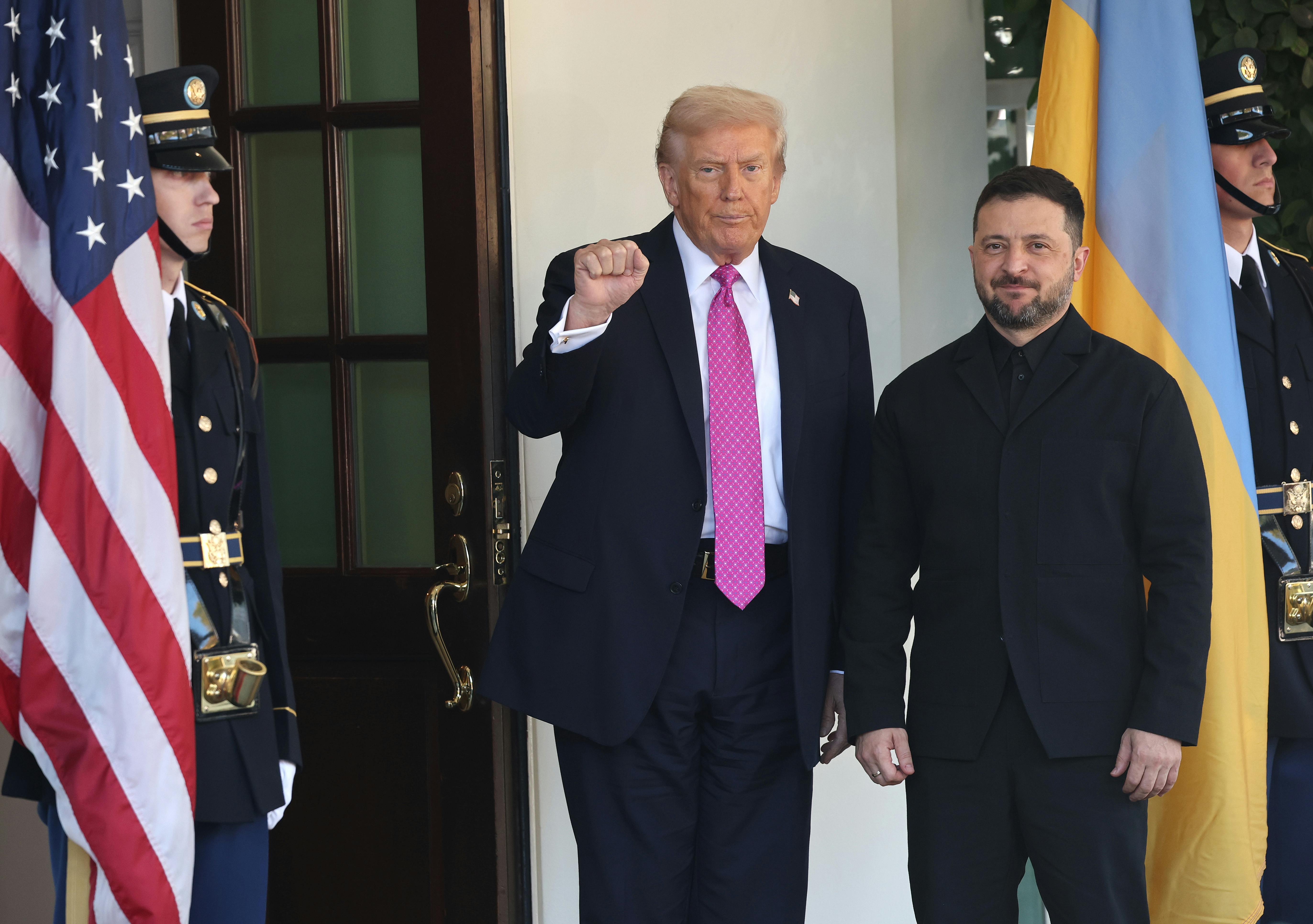 Donald Trump raises his fist while standing next to Ukrainian President Volodymyr Zelenskiy in front of the White House