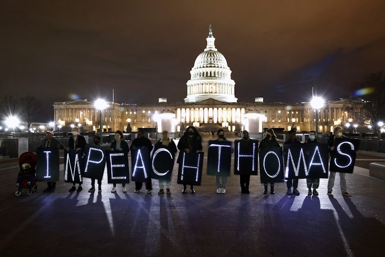 Protesters hold signs that read "Impeach Thomas" in front of the Capitol building in Washington, D.C.
