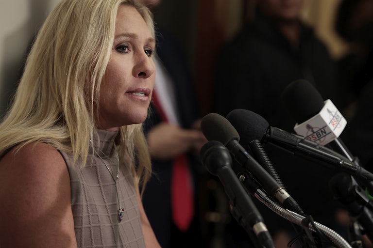 Marjorie Taylor Greene speaks into several microphones.