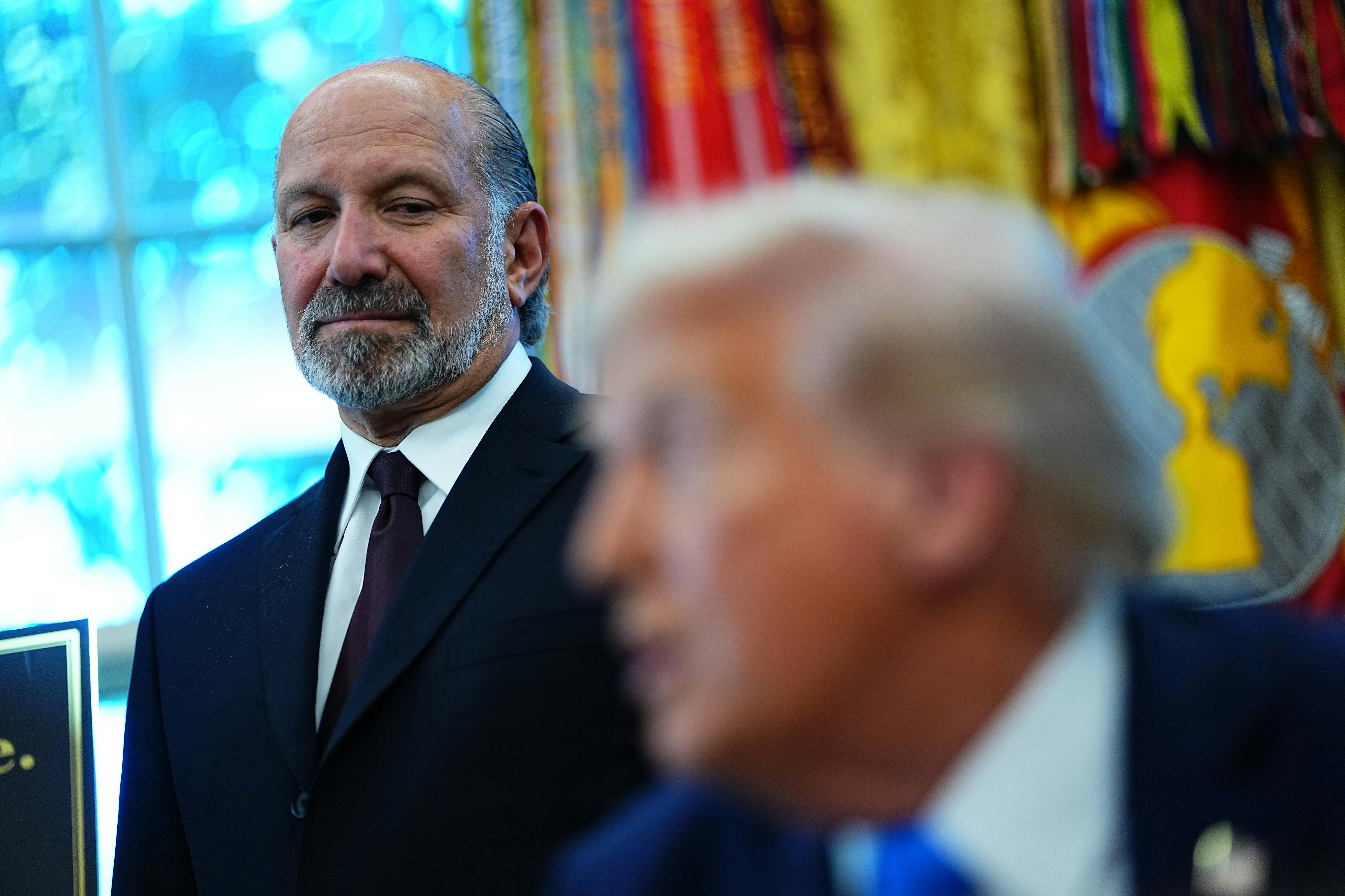 Commerce Secretary Howard Lutnick looks on as Donald Trump speaks.