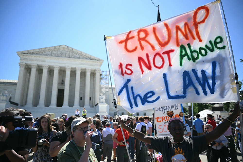 People hold anti-Trump signs in front of the U.S. Supreme Court on July 1 in Washington, D.C.