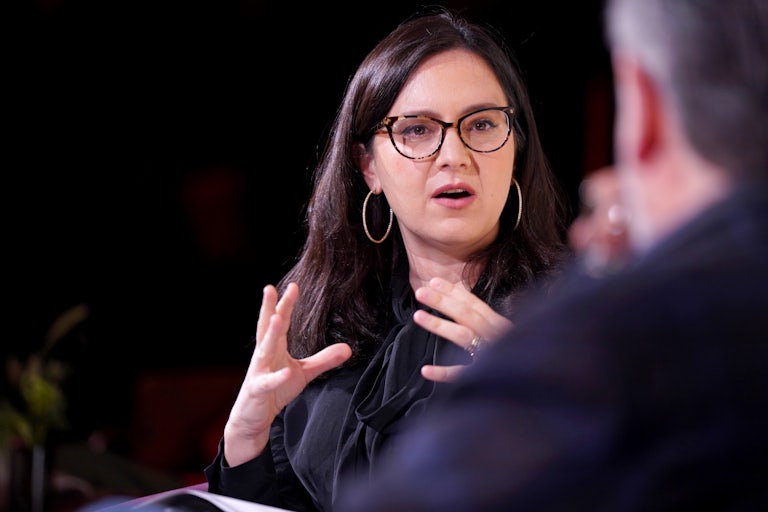 Bari Weiss speaks while a man (whose face is not pictured) listens to her