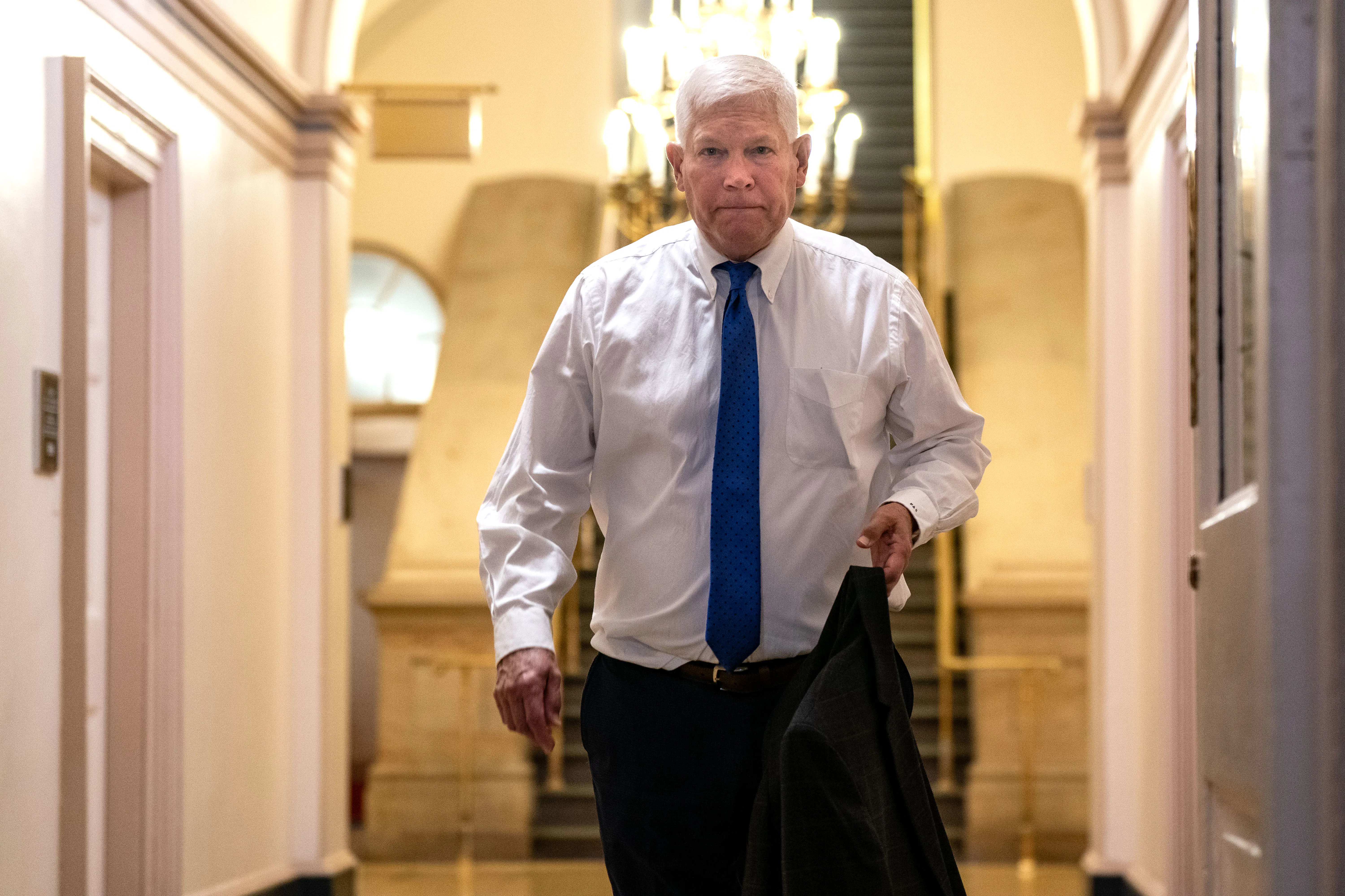 Representative Pete Sessions holds his suit jacket as he walks in the Capitol.