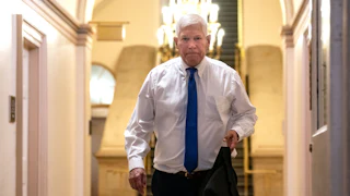 Representative Pete Sessions holds his suit jacket as he walks in the Capitol.