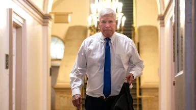 Representative Pete Sessions holds his suit jacket as he walks in the Capitol.
