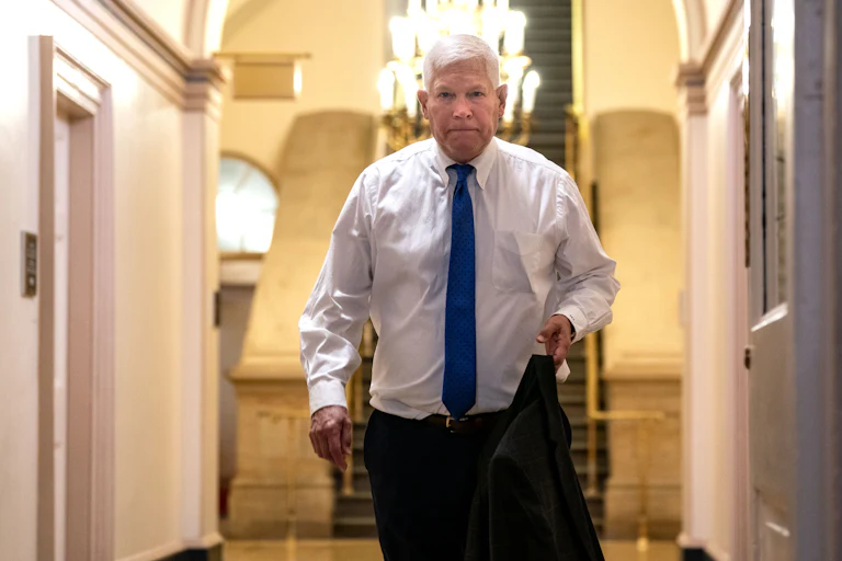 Representative Pete Sessions holds his suit jacket as he walks in the Capitol.