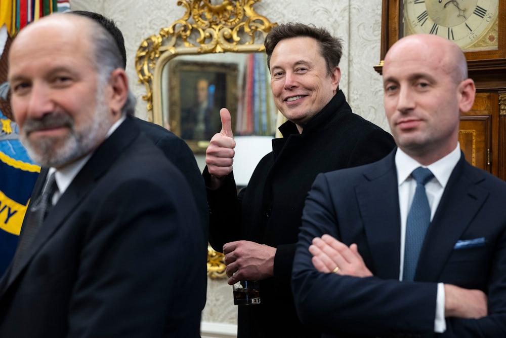 Elon Musk smiles and gives a thumbs-up sign, while standing between Howard Lutnick and Stephen Miller.