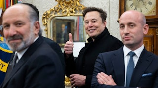 Elon Musk smiles and gives a thumbs-up sign, while standing between Howard Lutnick and Stephen Miller.