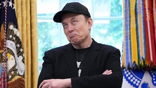 Elon Musk purses his lips and makes a dumb face while crossing his arms in the Oval Office