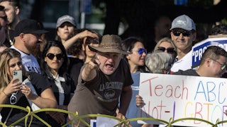 A man points at the camera while another demonstrator holds a sign reading "Tach ABC Not LGBTQ"