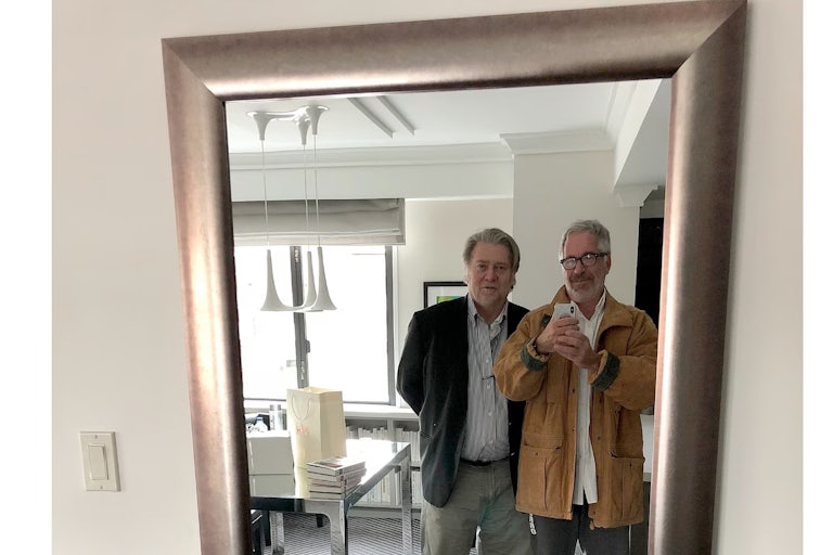 Jeffrey Epstein smiles and holds up a phone to take a photo of him and Steve Bannon as they look into a mirror.