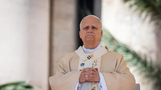 Pope Leo stands with a serious look on his face and his hands folded in front of his chest during Easter Mass in St. Peter's Square