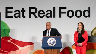 Robert F. Kennedy Jr. leans forward slightly and speaks at a podium in front of a banner that says, "Eat Real Food." Agriculture Secretary Brooke Rollins stands next to him.