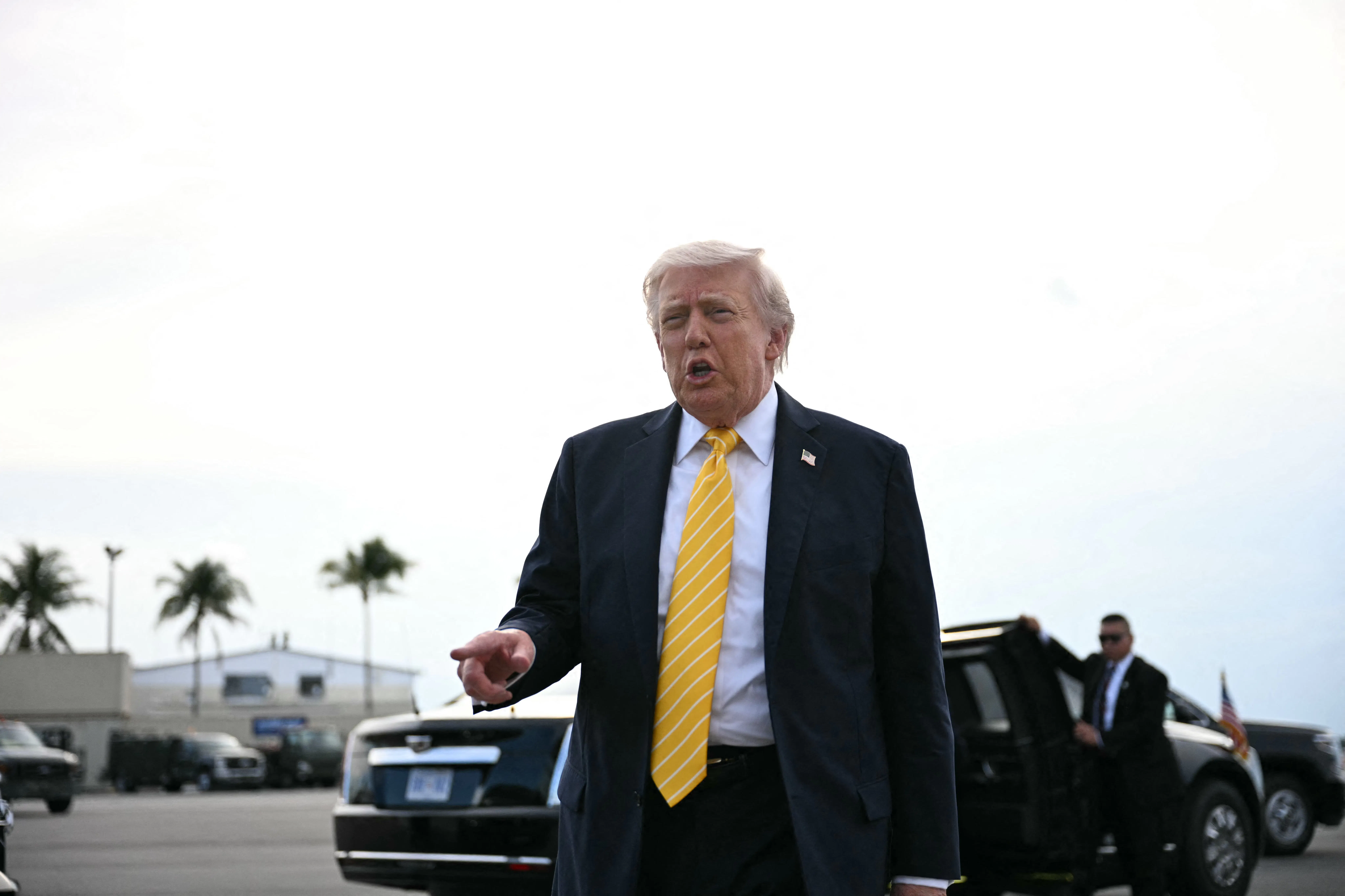 Doanld Trump points as he stands near a car