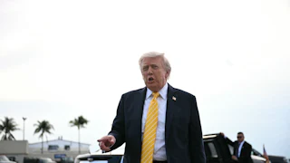 Doanld Trump points as he stands near a car