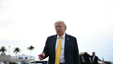 Doanld Trump points as he stands near a car
