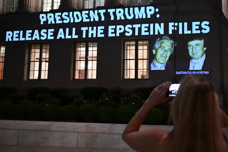 A person takes a photo as a message calling on President Donald Trump to release all files related to Jeffrey Epstein is projected onto the US Chamber of Commerce building across from the White House.