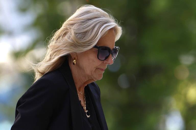 Jill Biden wears sunglasses and walks outdoors, looking downward