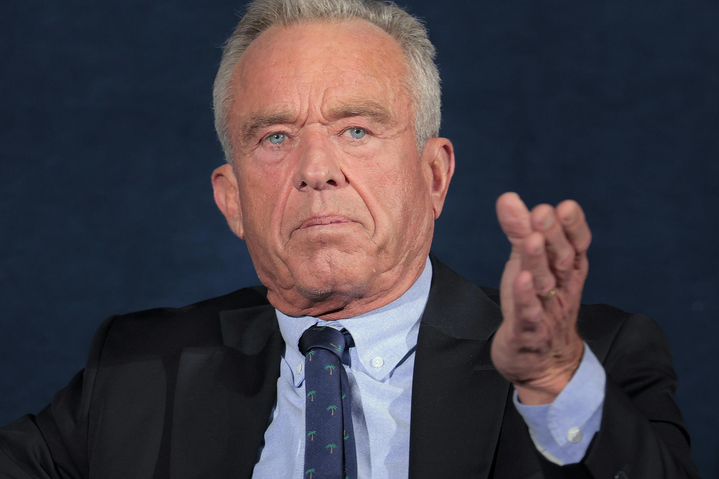 Robert F. Kennedy Jr. gestures while sitting on stage during an event