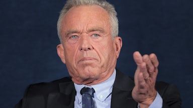 Robert F. Kennedy Jr. gestures while sitting on stage during an event