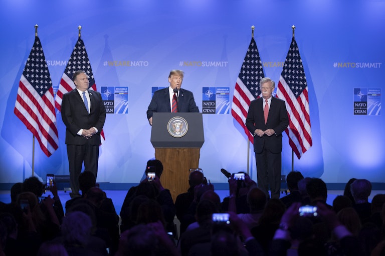Donald Trump speaks at a podium while flanked by Mike Pompeo and John Bolton