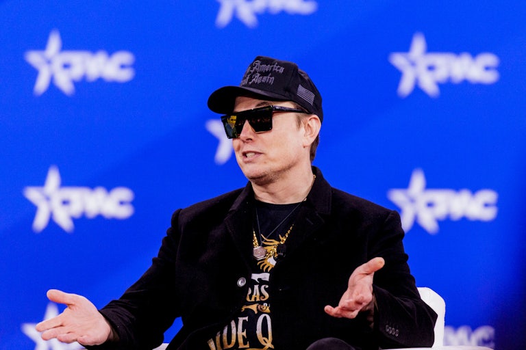 Elon Musk gestures while sitting onstage at CPAC