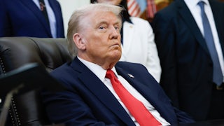 Donald Trump purses his lips while sitting at his desk in the Oval Office