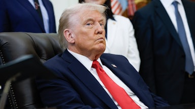 Donald Trump purses his lips while sitting at his desk in the Oval Office