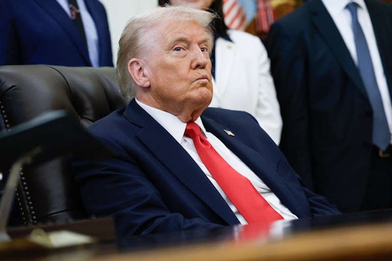 Donald Trump purses his lips while sitting at his desk in the Oval Office